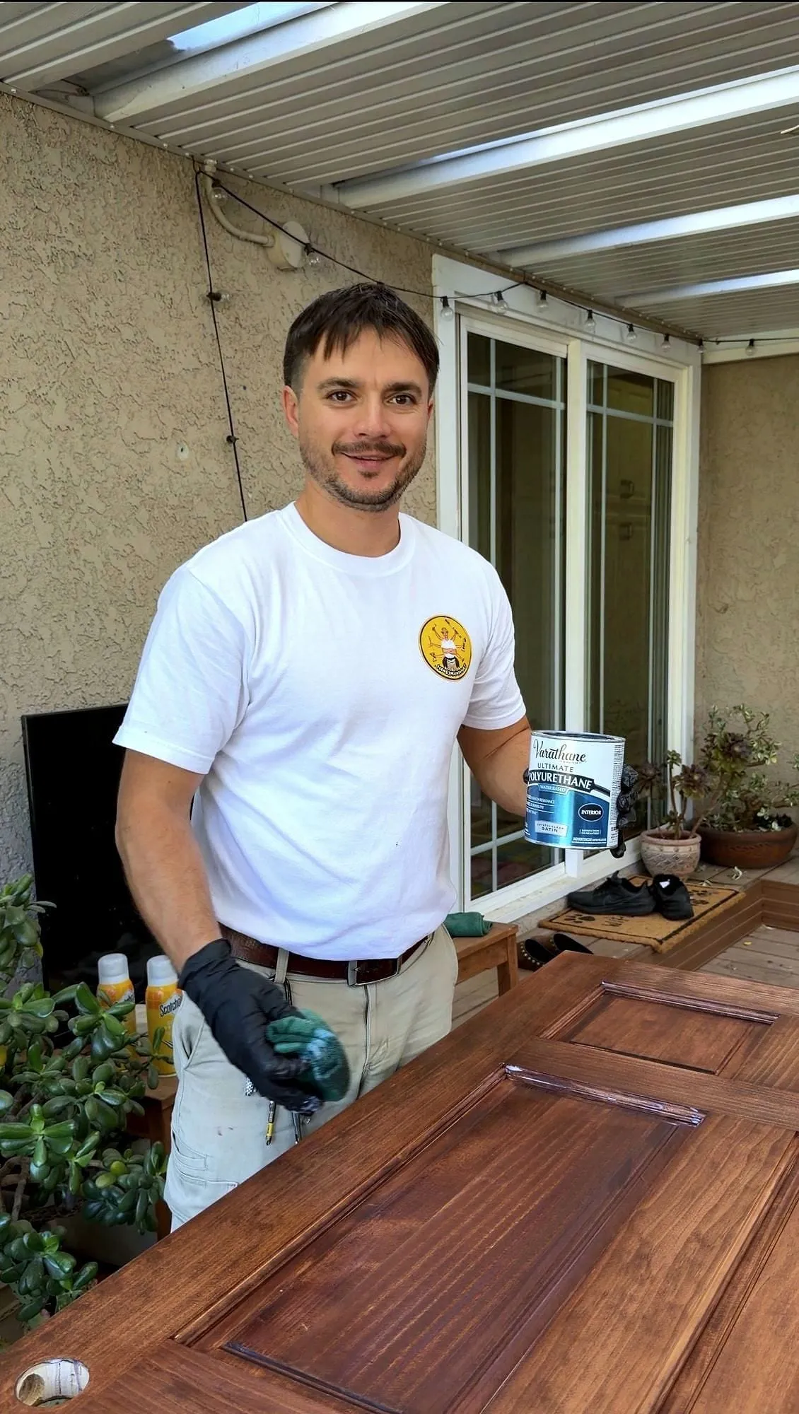Serj refinishing a solid wood door, polyurethane can in hand