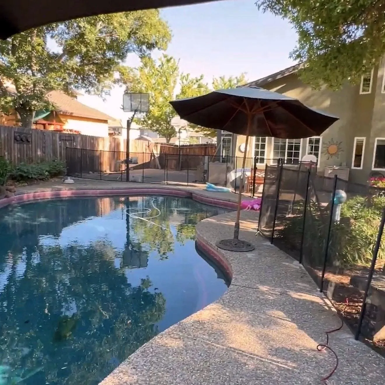 Black mesh pool safety fence installed around a Sacramento-area pool deck