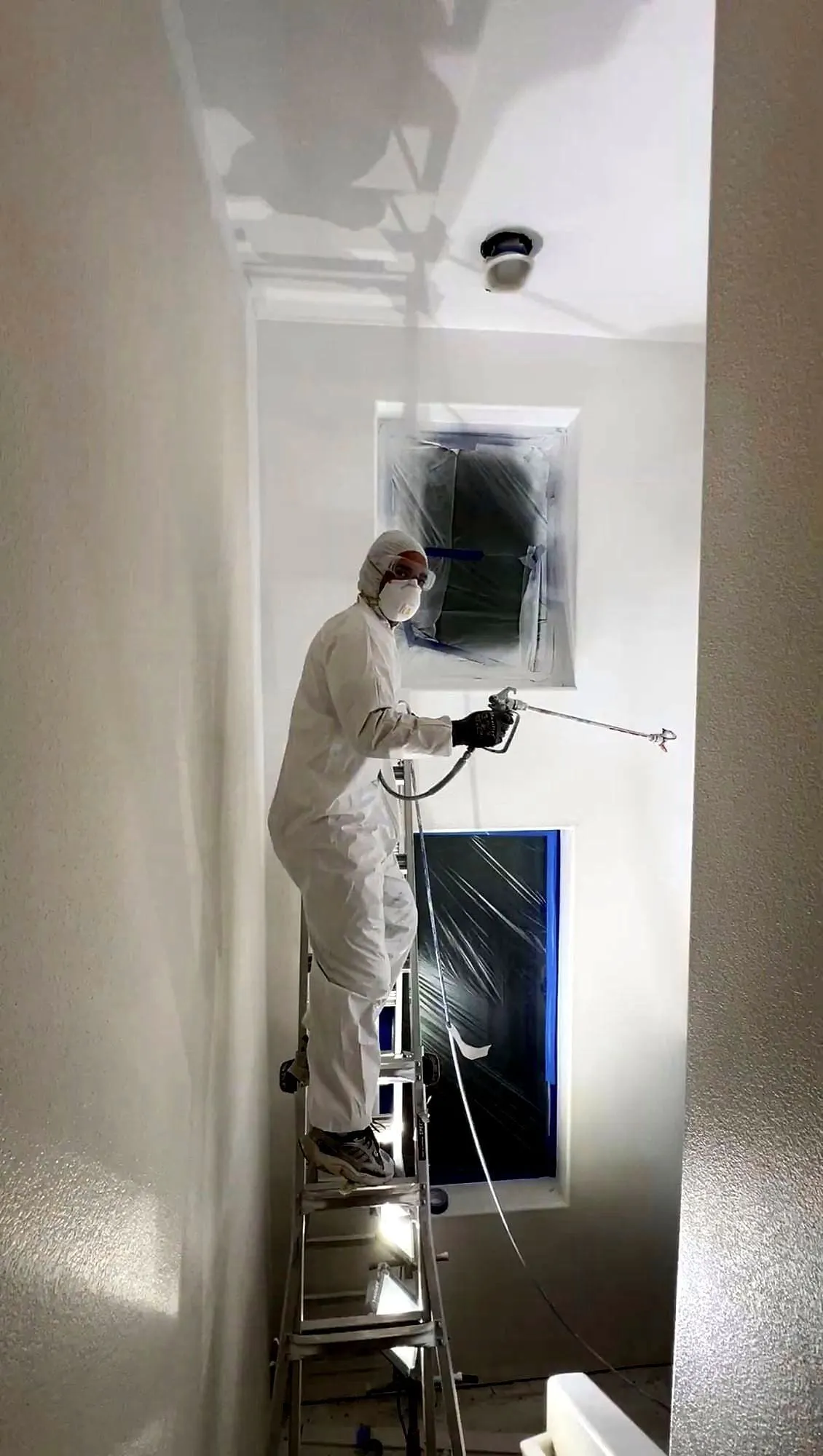 Spraying a fresh coat of paint on an interior wall in full protective gear